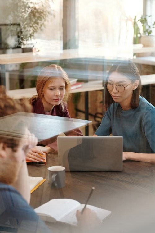 Three colleagues discussing work around a laptop